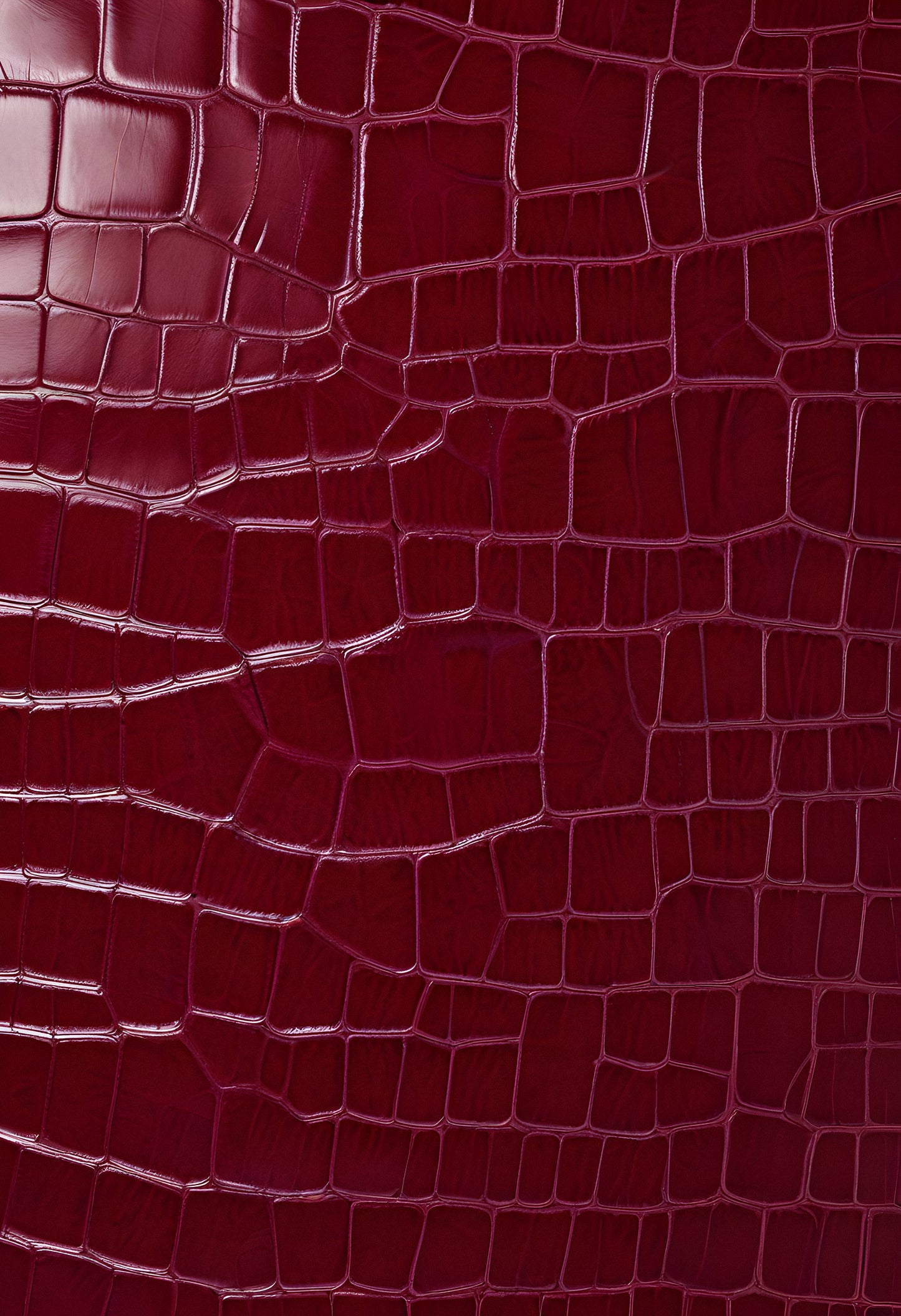 Rich burgundy crocodile leather texture with intricate patterns showcasing luxury and craftsmanship