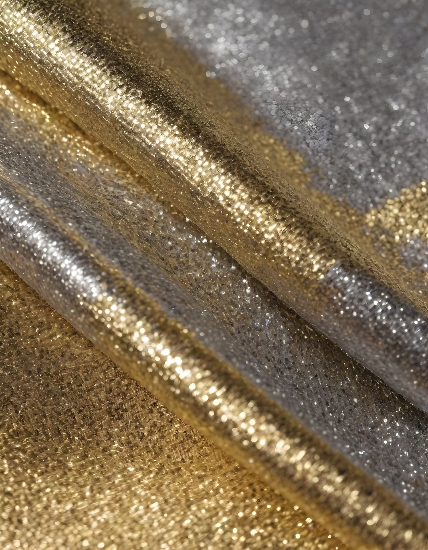 Metallic golden and silver fabric creates elegant textures with intricate folds and reflections under soft lighting