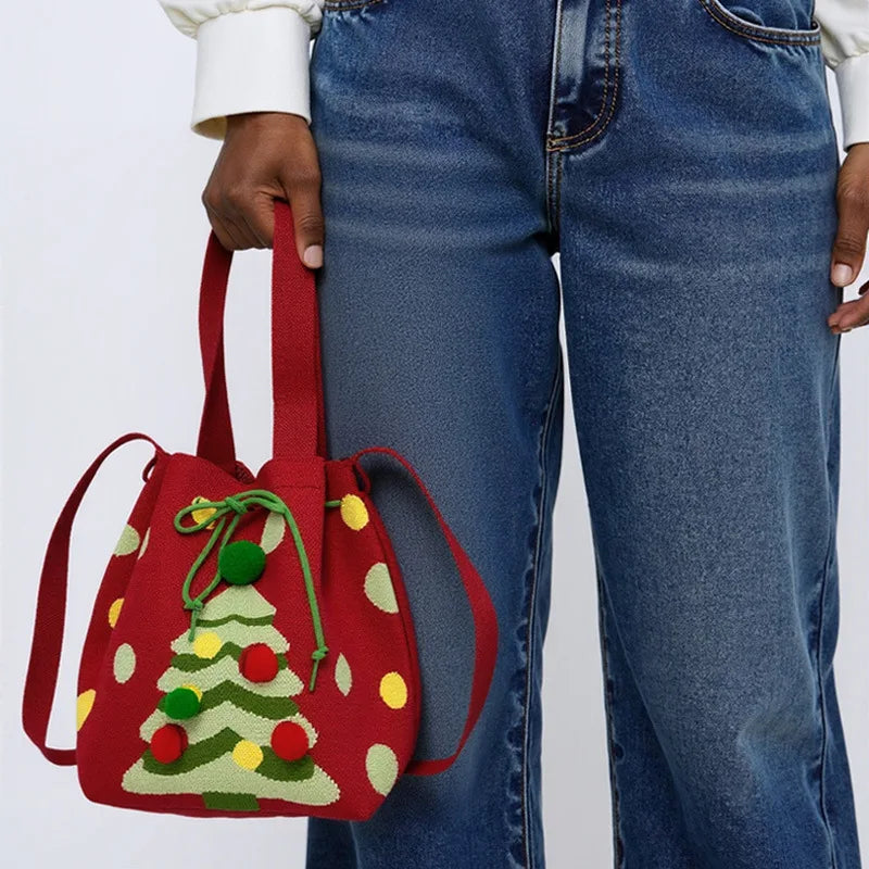 Red handbag with Christmas tree design held by a person wearing blue jeans.
