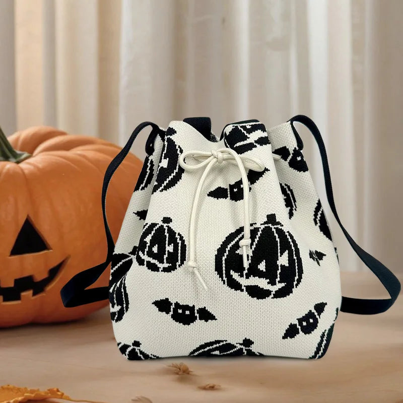 White drawstring bag with black pumpkin pattern next to a carved pumpkin on a wooden surface.