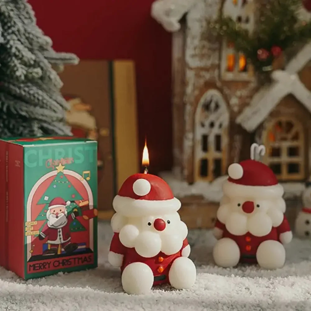 Two Santa Claus candles with a Christmas-themed box in the background