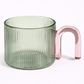 Green glass mug with a pink handle on a white background