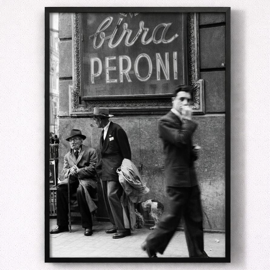 Framed black and white photo of people on a street with a Peroni sign.