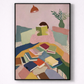 Framed artwork of a person reading a book on a colorful couch with books scattered around.