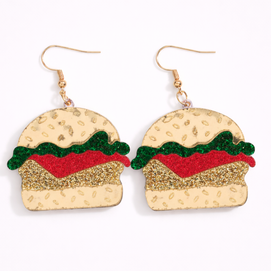 Hamburger-shaped earrings with gold bun, red patty, and green lettuce on a white background