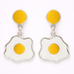Fried egg-shaped earrings with yellow centers on a white background