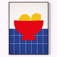 Framed artwork of a red bowl with yellow lemons on a blue grid background