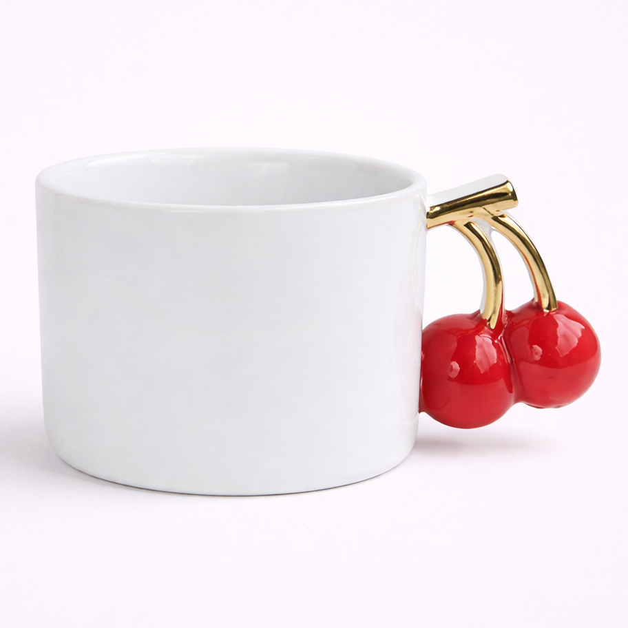 White mug with red cherries and gold stem on a white background