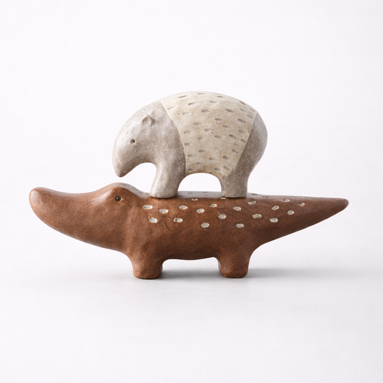 Ceramic sculpture of a bear on an alligator's back on a white background