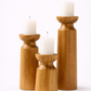 Three wooden candle holders with candles on a white background