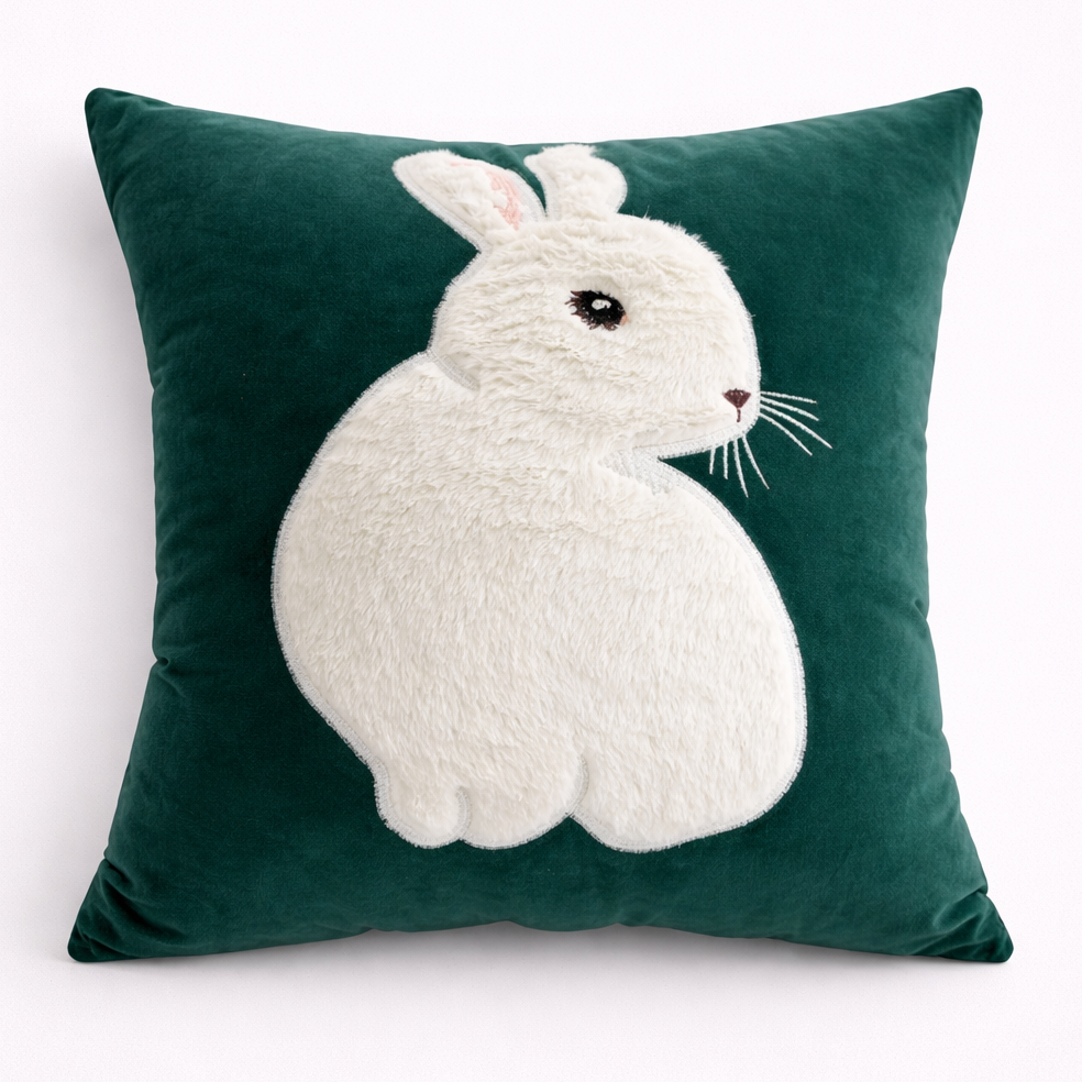 Green pillow with a white rabbit design on a white background