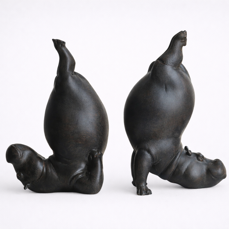 Two bronze sculptures of seals in yoga poses on a white background