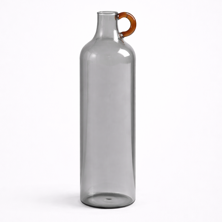 Clear glass bottle with a brown handle on a white background