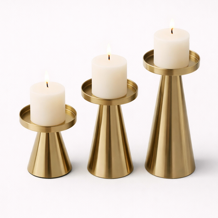Three gold candle holders with white candles on a white background