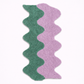 Wavy-patterned rug with green and pink stripes on a white background