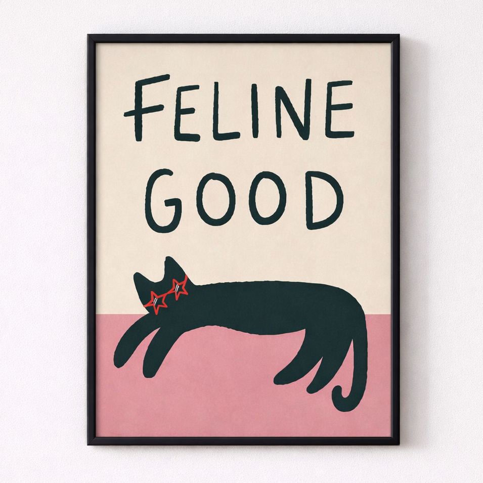 Framed artwork with a black cat illustration and 'Feline Good' text on a beige and pink background.