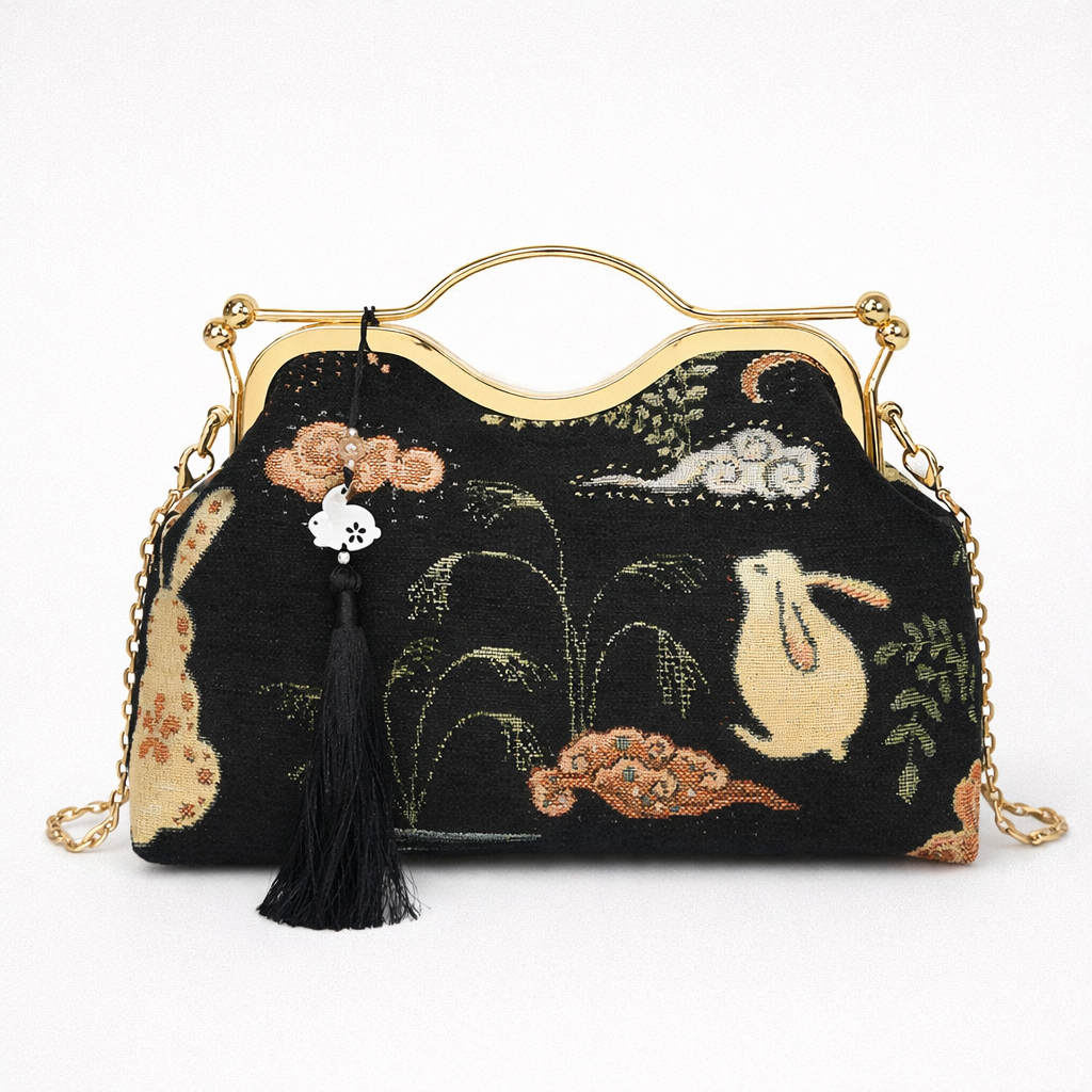 Embroidered handbag with gold chain and tassel on a white background
