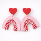 Pair of earrings with pink arches and red hearts on a white background