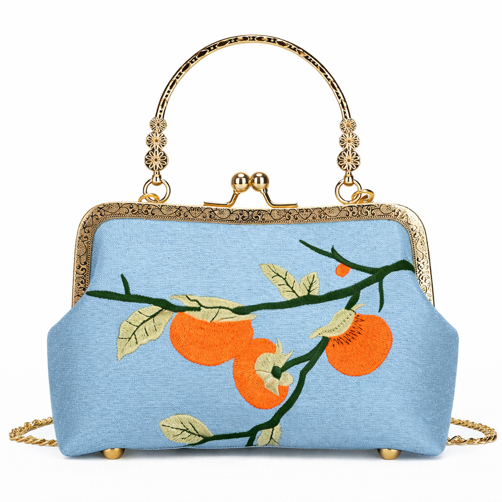 Blue handbag with orange fruit design and gold accents on a white background