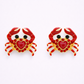 Pair of crab-shaped earrings with red hearts on a white background