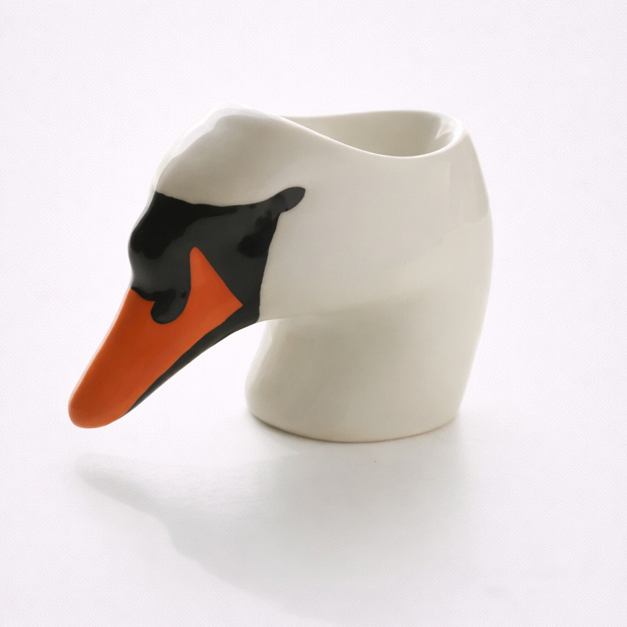 Ceramic mug shaped like a swan with a black and orange beak on a white background