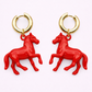 Red horse-shaped earrings with gold hoop backs on a white background