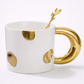 White mug with gold handle and decorative elements on a white background