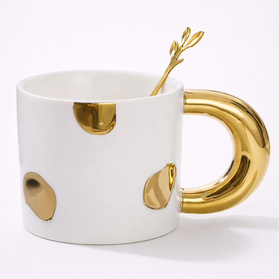 White mug with gold handle and decorative elements on a white background