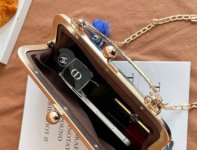 Gold clutch bag with a chain on a brown surface