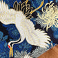 Embroidered fabric with a white crane and floral patterns on a blue background