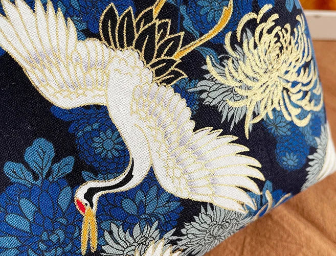 Embroidered fabric with a white crane and floral patterns on a blue background