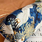 Embroidered clutch with crane design on a blue background