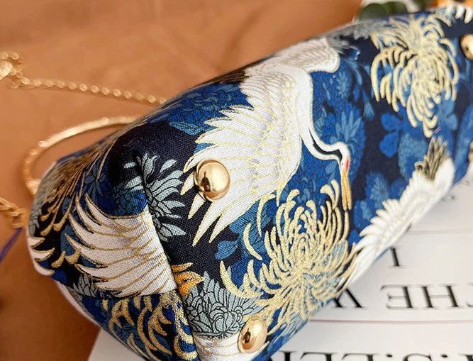 Embroidered clutch with crane design on a blue background