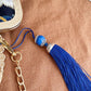 Blue tassel keychain with gold chain on a brown surface
