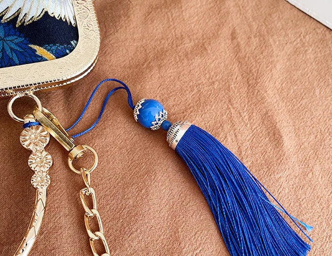Blue tassel keychain with gold chain on a brown surface