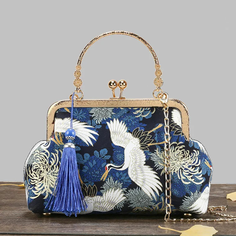 Embroidered handbag with crane design on a wooden surface