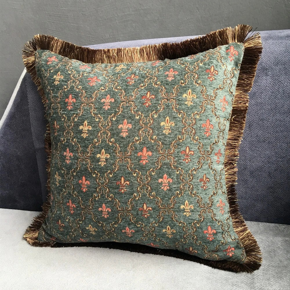 Decorative pillow with intricate pattern and brown fringes on a gray sofa.