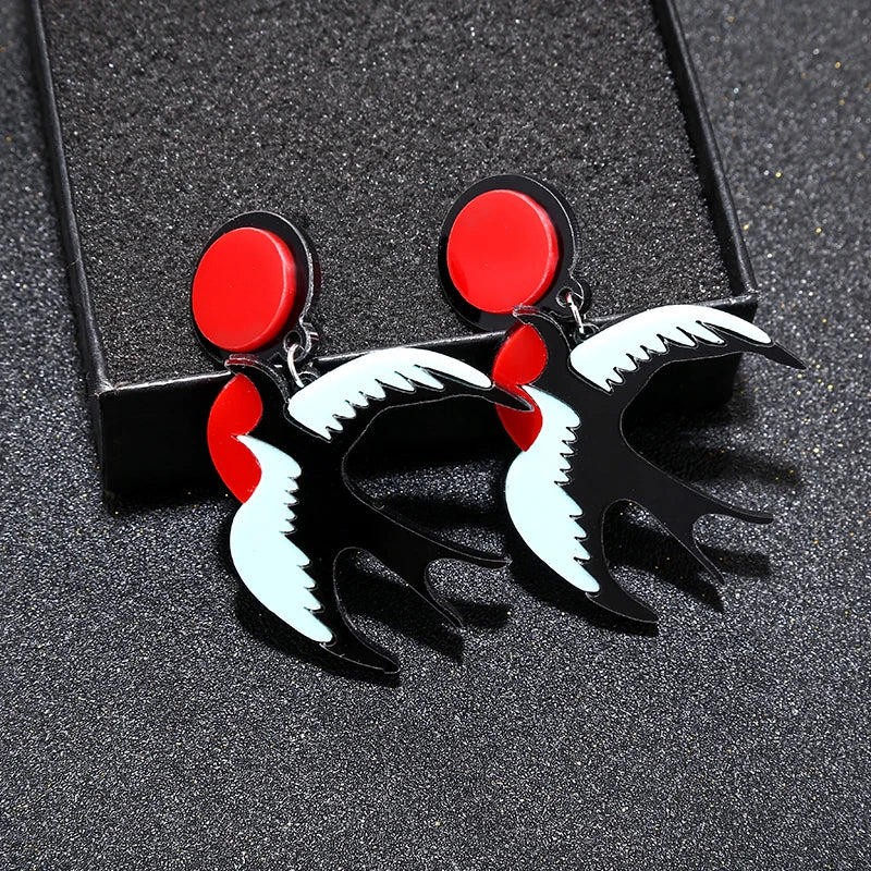 Pair of earrings with red, black, and white design on a dark textured background