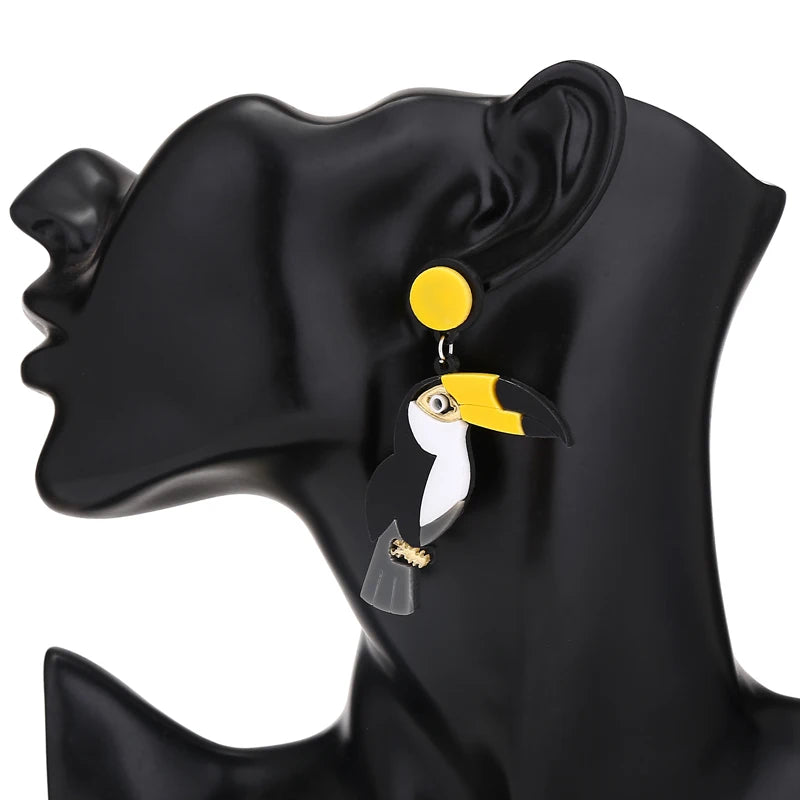 Toucan-shaped earrings on a black mannequin ear