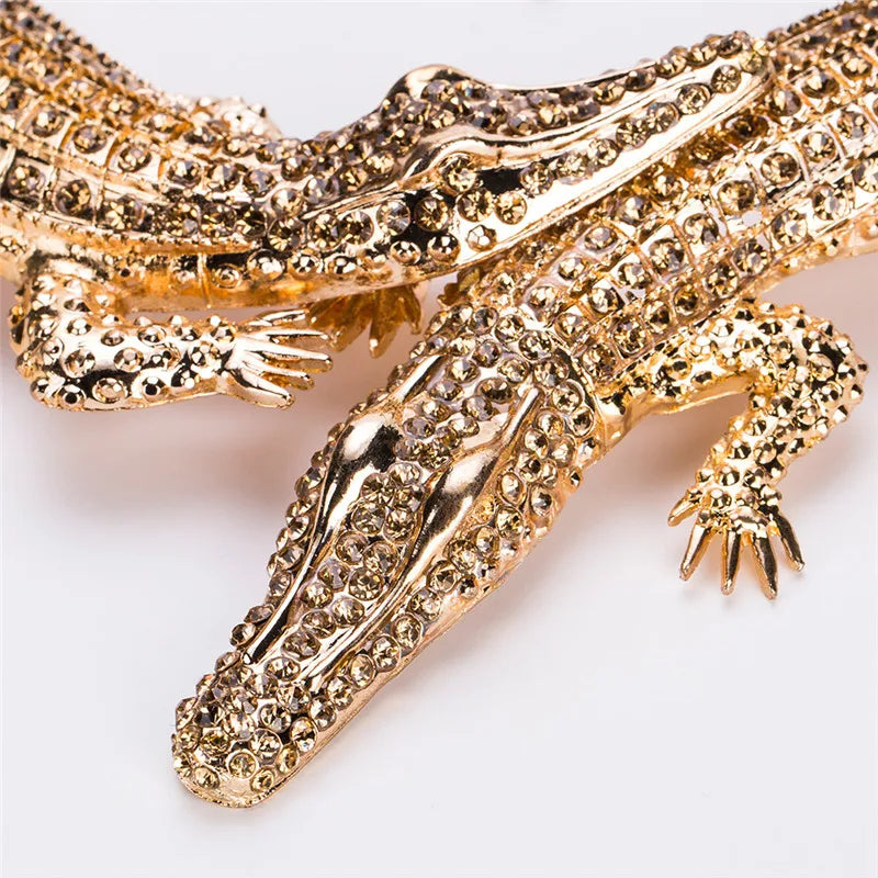 Gold crocodile-shaped brooch with gemstones on a white background