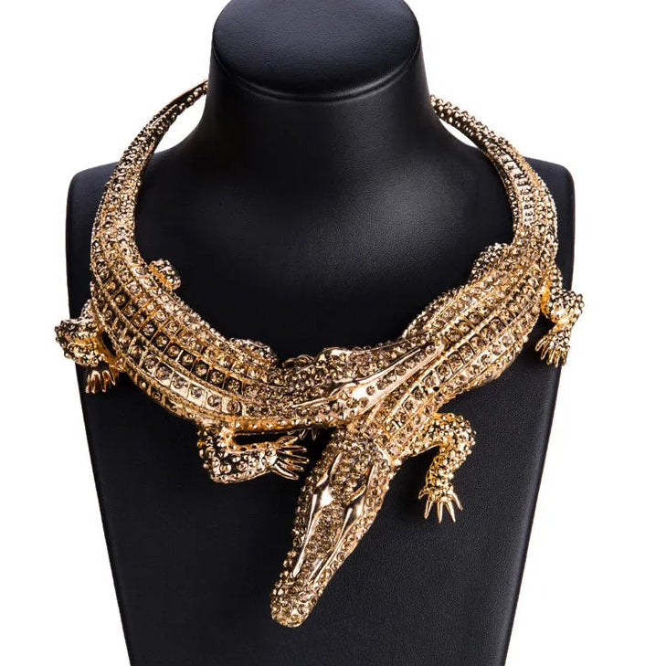 Gold crocodile-shaped necklace on a black mannequin