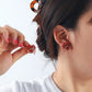 Person wearing red crab-shaped earrings with a plain background