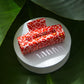 Red and white patterned box on a white platform with green leaves in the background