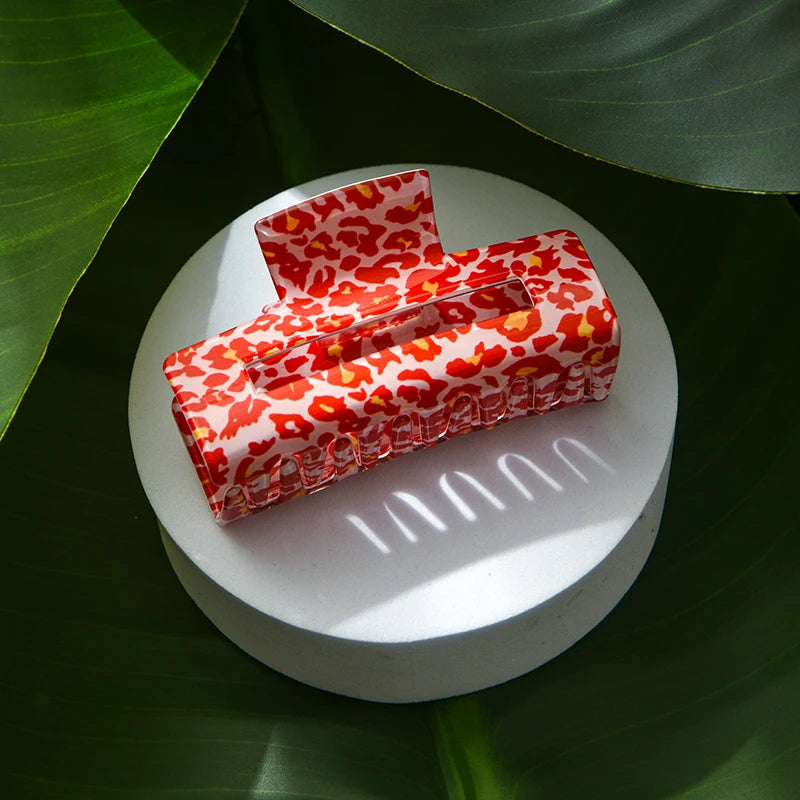 Red and white patterned box on a white platform with green leaves in the background