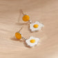 Fried egg-shaped earrings on a beige fabric background