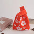 Red fabric bag with floral patterns on a light surface
