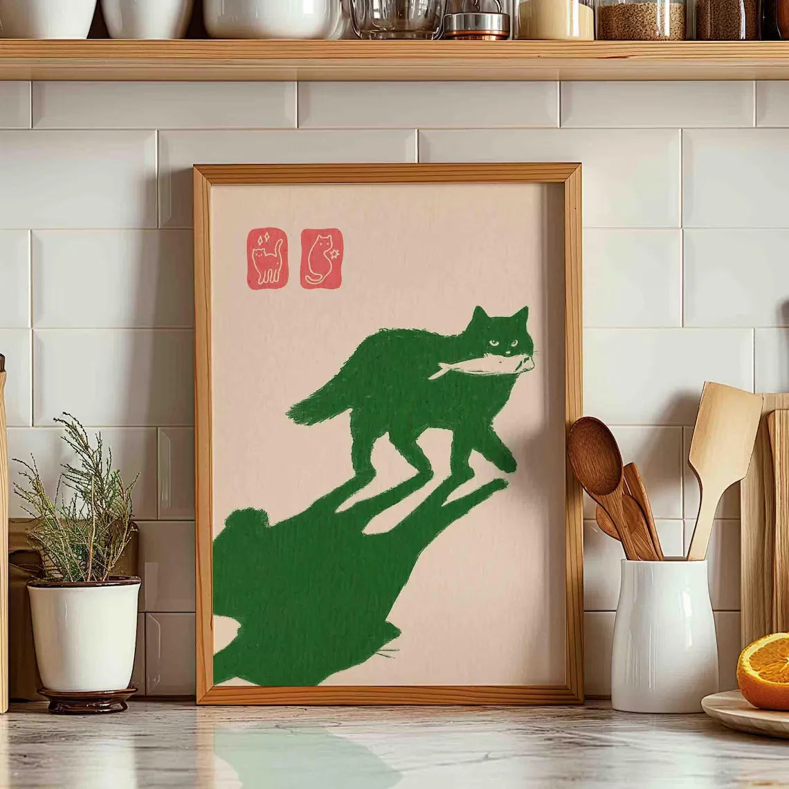 Framed artwork of a green cat and its shadow on a beige background, displayed in a kitchen.