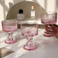 Set of pink glass dessert dishes on a white surface with a neutral background