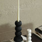Black candle holder with a white candle on a textured surface