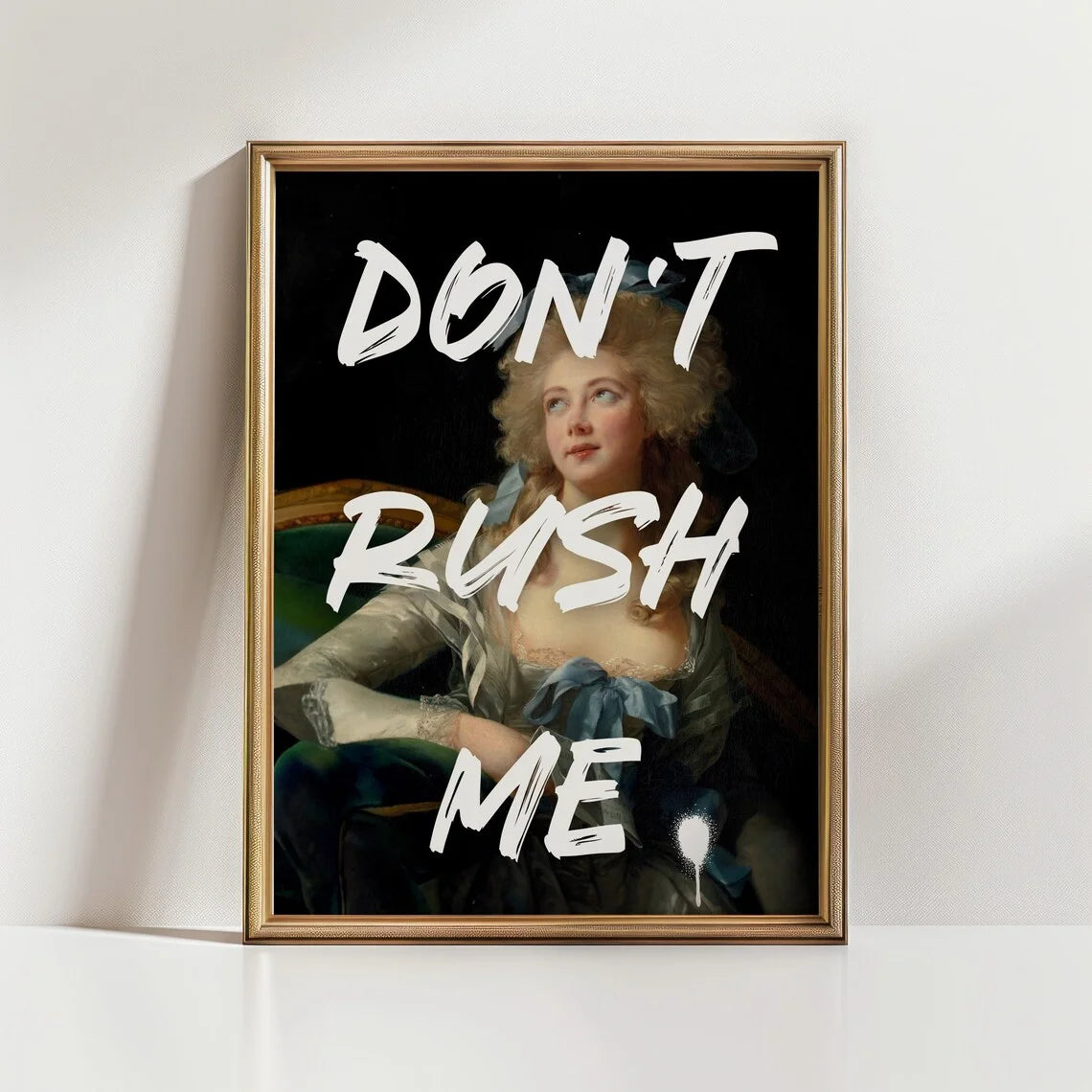 Framed artwork with a classical portrait and text 'DON'T RUSH ME' on a white wall.